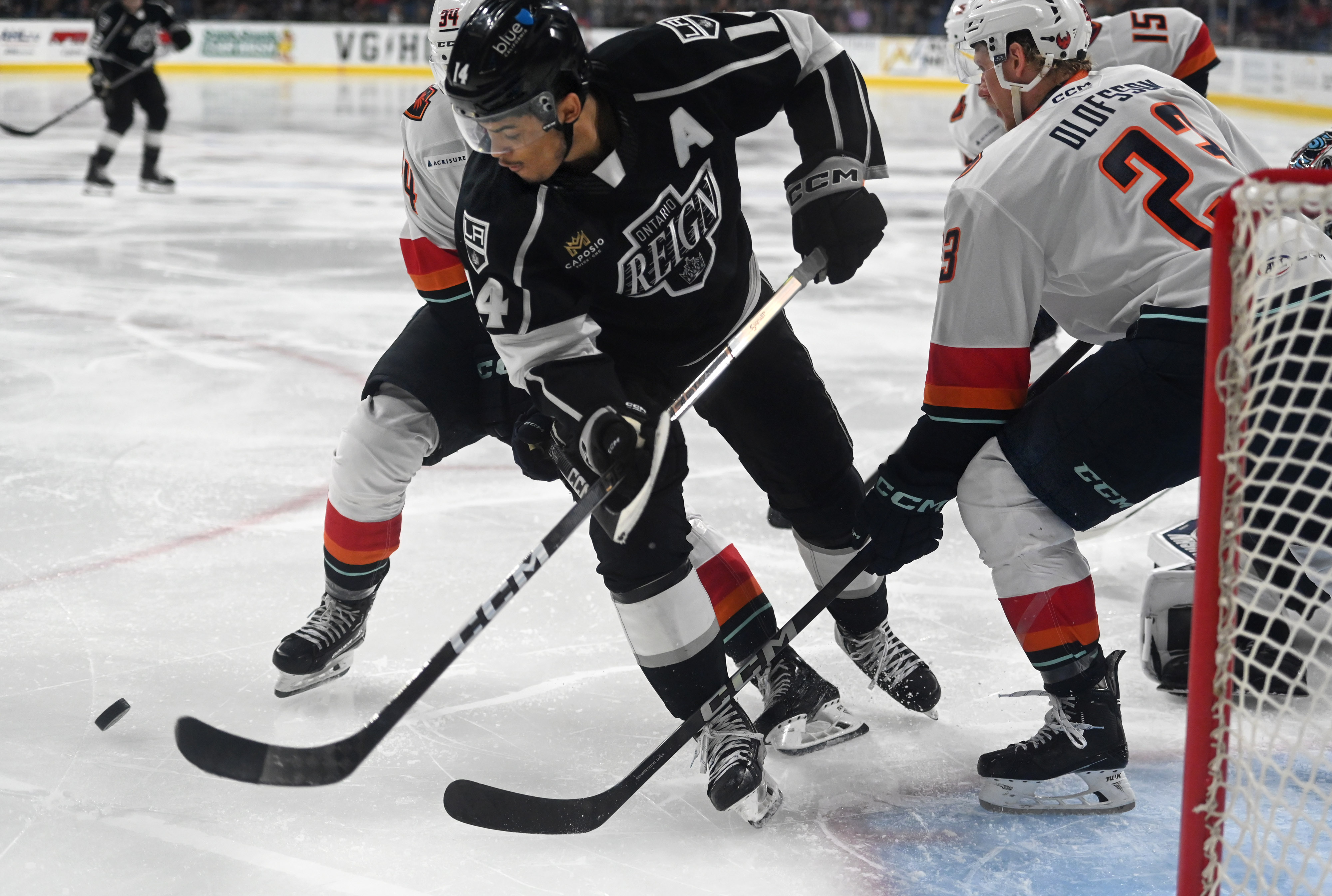 Ontario Reign’s Akil Thomas tries to control the puck between...