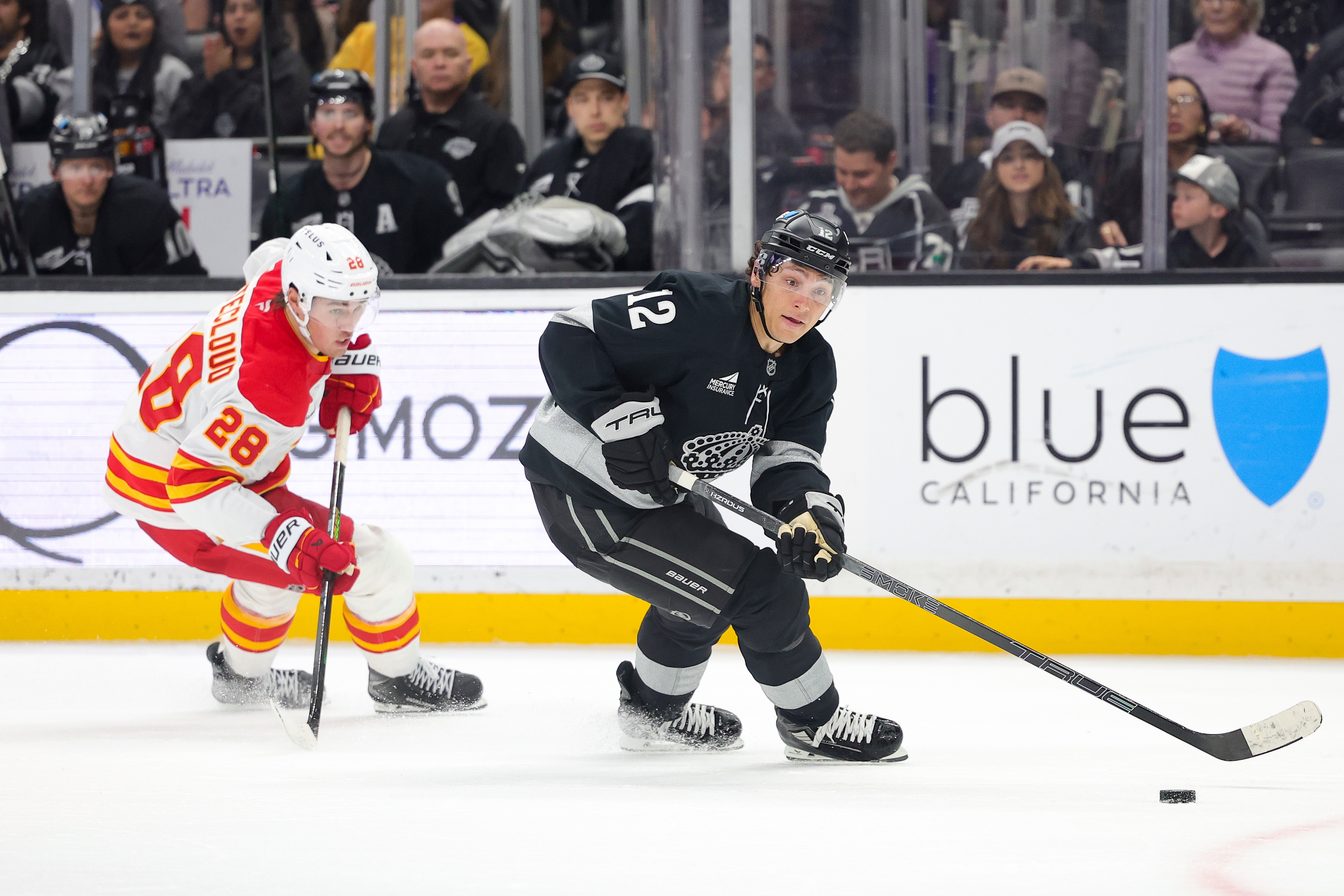Kings left wing Trevor Moore, right, moves the puck past...