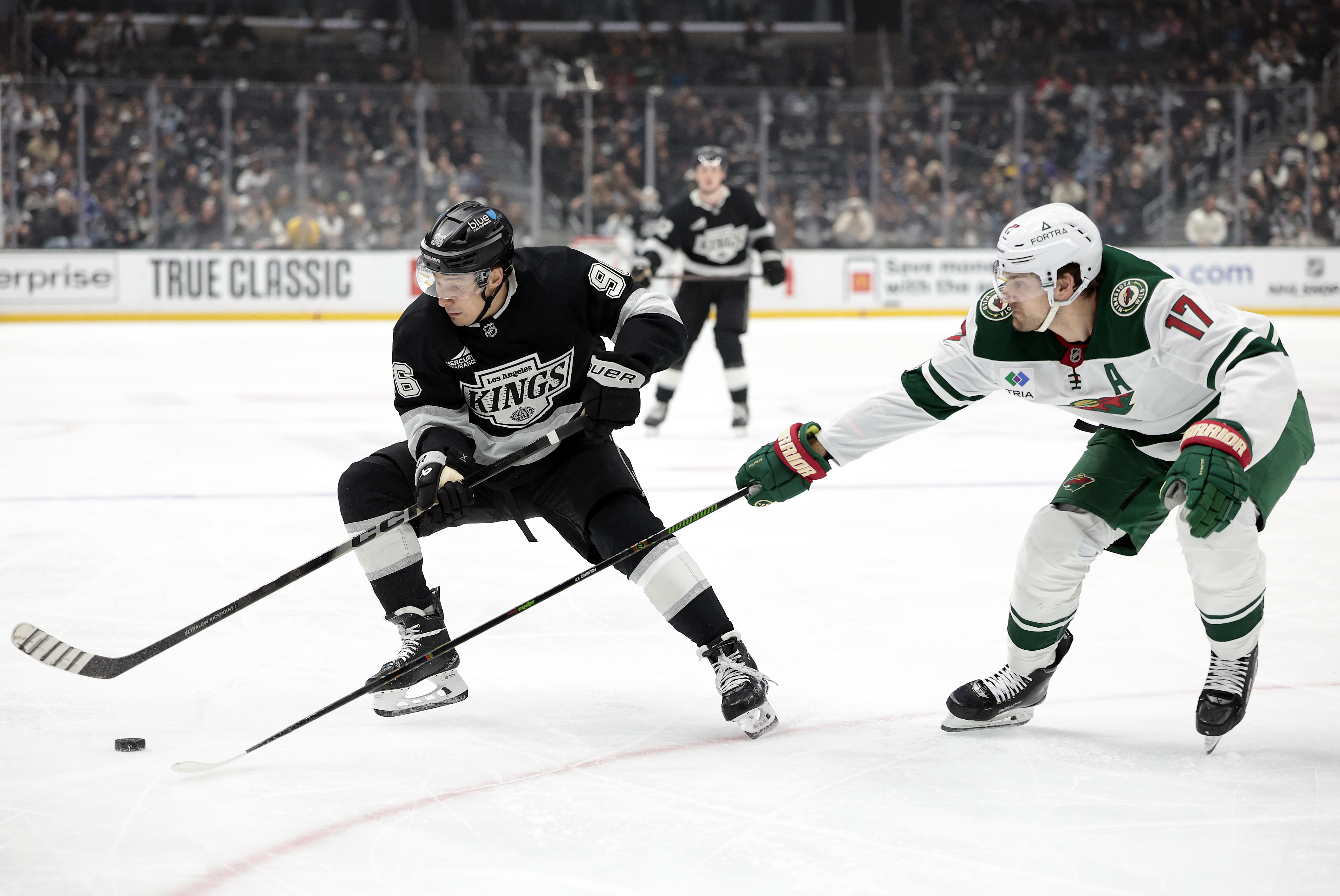 The Kings’ Andrei Kuzmenko, left, skates with the puck as...