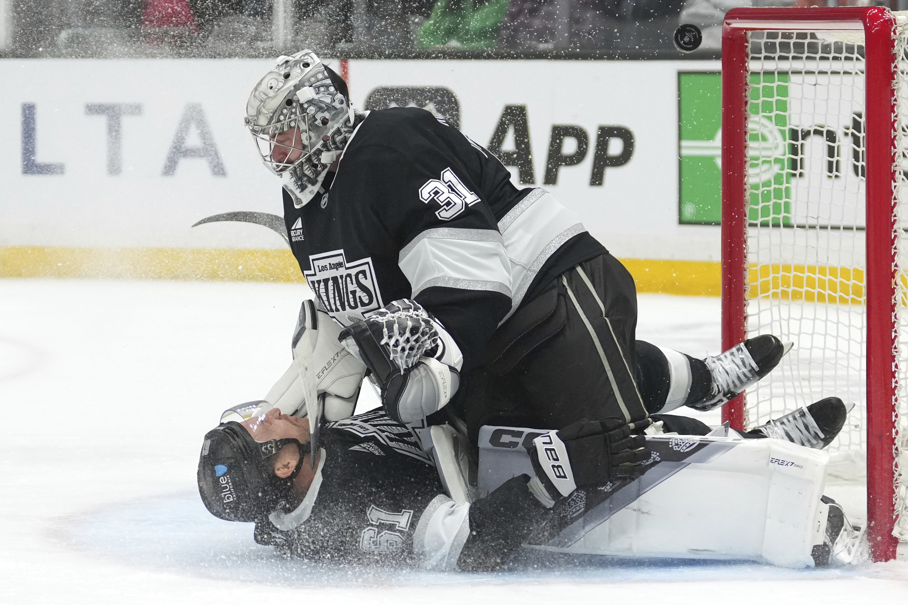 Kings center Trevor Lewis, below, collides with goaltender David Rittich...