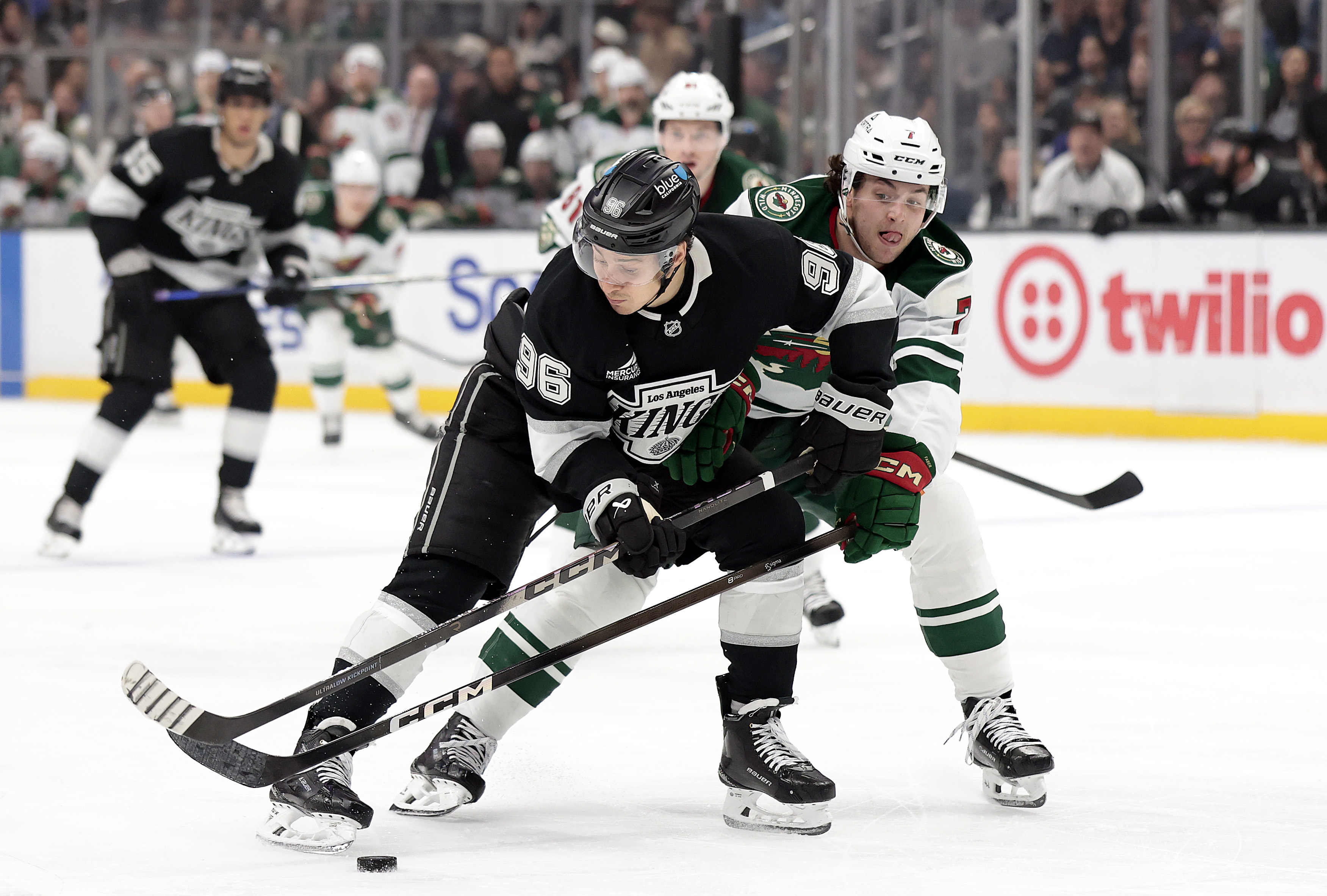The Kings’ Andrei Kuzmenko, left, vies for the puck against...