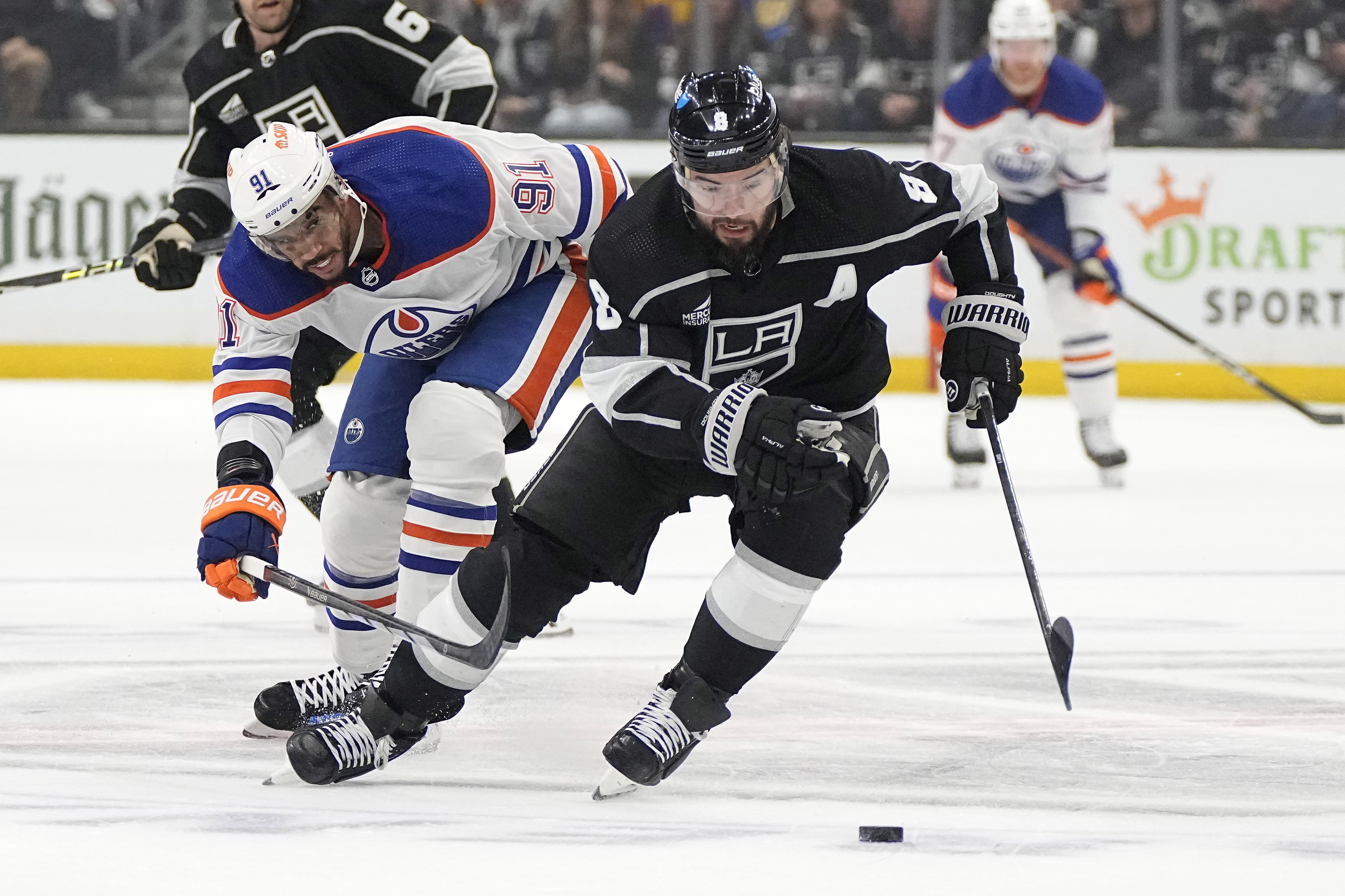 Los Angeles Kings defenseman Drew Doughty, right, takes the puck...