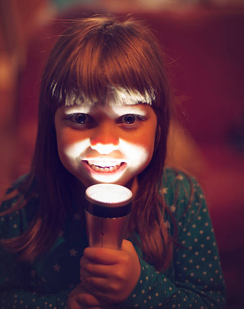 girl-trying-to-scare-someone-with-flash-light-picture-id524154029